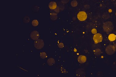 Siyah arkaplanda koyu soyut altın bokeh parıltısı
