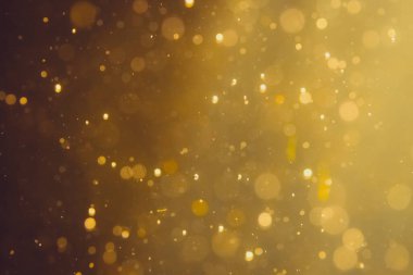Siyah arkaplanda koyu soyut altın bokeh parıltısı