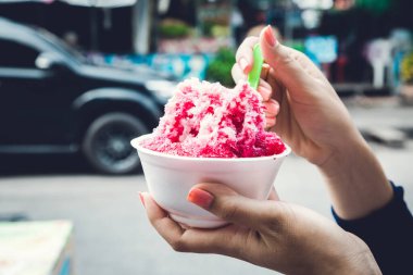 Kırmızı şuruplu buzlu tatlılar ve doğal arka planda el ele tutuşan kadınlarda tatlı süt.
