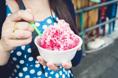 Kırmızı şuruplu buzlu tatlılar ve doğal arka planda el ele tutuşan kadınlarda tatlı süt.