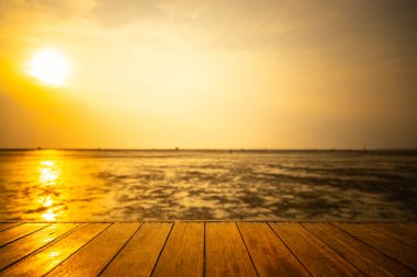 Ahşap zemin, günbatımı arka planında su düştüğünde denize doğru uzanıyor.