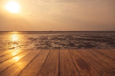Ahşap zemin, günbatımı arka planında su düştüğünde denize doğru uzanıyor.