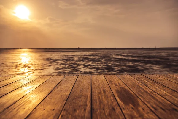 Ahşap zemin, günbatımı arka planında su düştüğünde denize doğru uzanıyor.