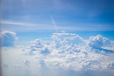 Gökyüzü ve yerden görünen bulutlar, açık renkli arka planlı bir uçaktan görüldü.