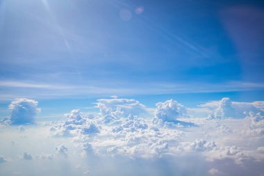 Gökyüzü ve yerden görünen bulutlar, açık renkli arka planlı bir uçaktan görüldü.
