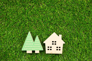 Yapay çimlerin üzerinde ağaç olan küçük ahşap bir ev.