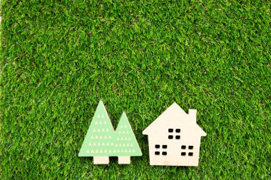 Yapay çimlerin üzerinde ağaç olan küçük ahşap bir ev.