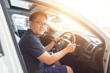 Yakışıklı Asyalı adam mutlu bir araba kullanmayı seviyor.