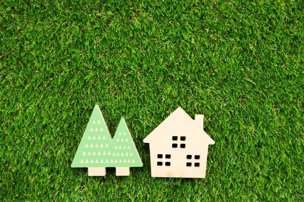 Yapay çimlerin üzerinde ağaç olan küçük ahşap bir ev.