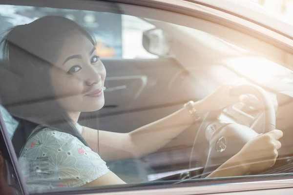 beautiful Asian woman drives a car with a glass door in the background
