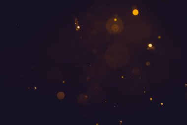 Siyah arkaplanda koyu soyut altın bokeh parıltısı
