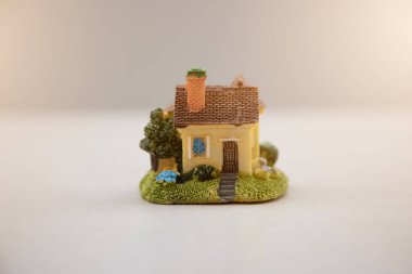 Kiremitli çatı altında sarıya boyanmış ev modeli bulanık doğal arka planda izole edilmiş..