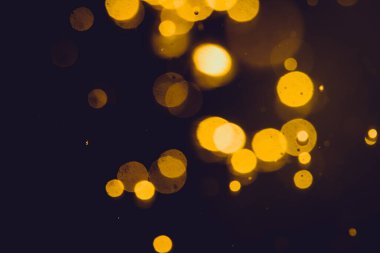 Siyah arkaplanda koyu soyut altın bokeh parıltısı