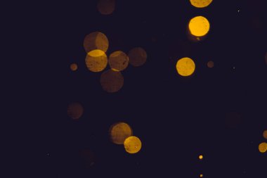 Siyah arkaplanda koyu soyut altın bokeh parıltısı
