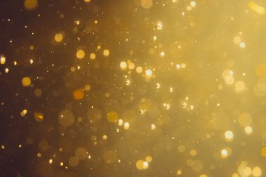Siyah arkaplanda koyu soyut altın bokeh parıltısı