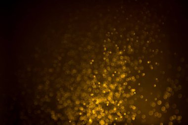Siyah arkaplanda koyu soyut altın bokeh parıltısı