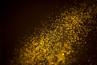 Siyah arkaplanda koyu soyut altın bokeh parıltısı