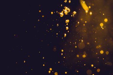 Siyah arkaplanda koyu soyut altın bokeh parıltısı