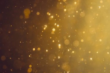 Siyah arkaplanda koyu soyut altın bokeh parıltısı