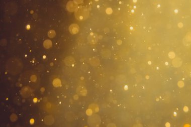 Siyah arkaplanda koyu soyut altın bokeh parıltısı