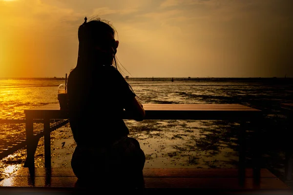 Women sitting and watching the sea at sunset nature background