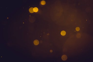 Siyah arkaplanda koyu soyut altın bokeh parıltısı