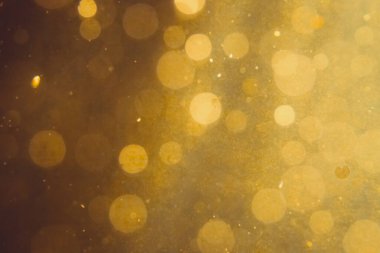 Siyah arkaplanda koyu soyut altın bokeh parıltısı