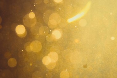 Siyah arkaplanda koyu soyut altın bokeh parıltısı
