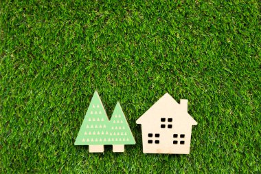 Yapay çimlerin üzerinde ağaç olan küçük ahşap bir ev.