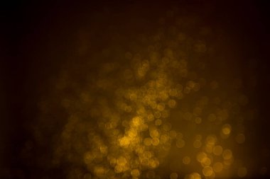 Siyah arkaplanda koyu soyut altın bokeh parıltısı