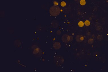 Siyah arkaplanda koyu soyut altın bokeh parıltısı