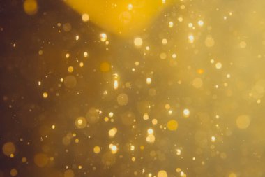 Siyah arkaplanda koyu soyut altın bokeh parıltısı