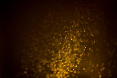 Siyah arkaplanda koyu soyut altın bokeh parıltısı