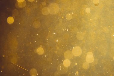 Siyah arkaplanda koyu soyut altın bokeh parıltısı