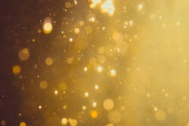 Siyah arkaplanda koyu soyut altın bokeh parıltısı