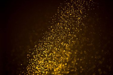 Siyah arkaplanda koyu soyut altın bokeh parıltısı