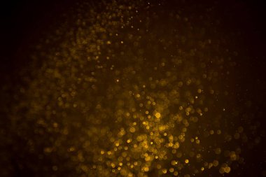 Siyah arkaplanda koyu soyut altın bokeh parıltısı