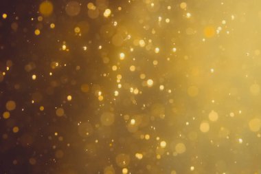 Siyah arkaplanda koyu soyut altın bokeh parıltısı