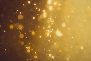 Siyah arkaplanda koyu soyut altın bokeh parıltısı