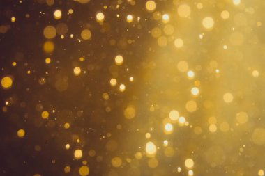 Siyah arkaplanda koyu soyut altın bokeh parıltısı