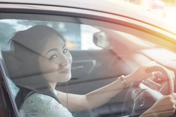 beautiful Asian woman drives a car with a glass door in the background