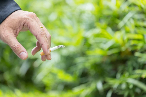 Mano Del Hombre Sosteniendo Cigarrillo Con Fondo Verde Natural —  Fotos de Stock