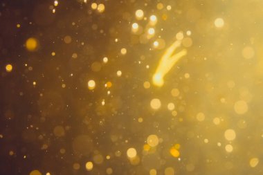 Siyah arkaplanda koyu soyut altın bokeh parıltısı