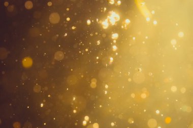 Siyah arkaplanda koyu soyut altın bokeh parıltısı