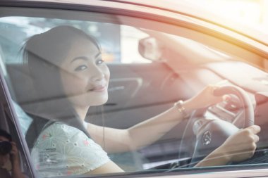 beautiful Asian woman drives a car with a glass door in the background