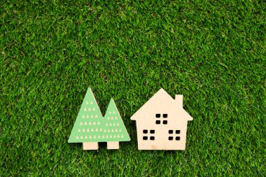 Yapay çimlerin üzerinde ağaç olan küçük ahşap bir ev.