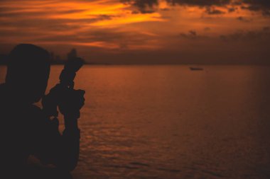 Gün batımı geçmişi olan siluet fotoğrafçı.