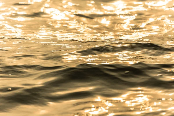 Water surface with moving wave of golden water reflecting