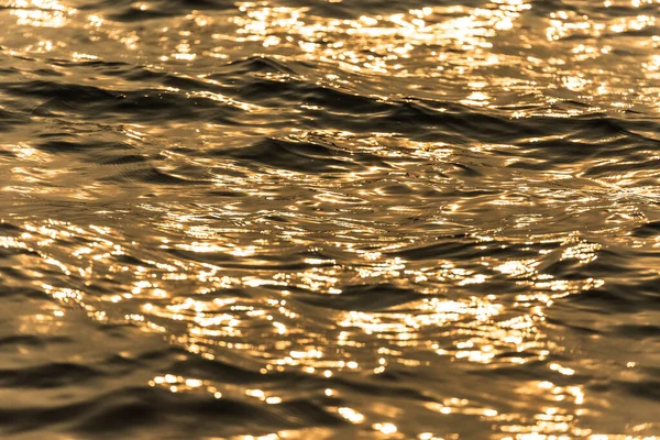 Water surface with moving wave of golden water reflecting