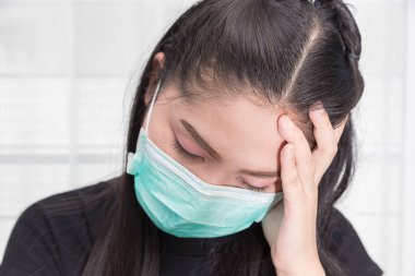 Asyalı kadın Covid hastalığından korunmak için tıbbi maske takıyor..